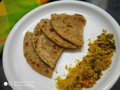 Soft, golden-brown stuffed parathas served with spicy turmeric lentil curry on a white plate. Perfect Indian breakfast or snack.