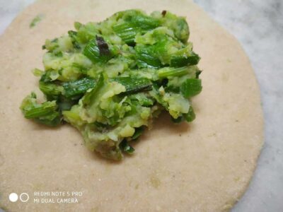 Chopped green vegetables filling on a dough circle for Indian paratha, ready for cooking or stuffing.