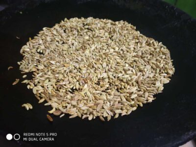Roasted fennel seeds on a black skillet for flavorful cooking and recipes.