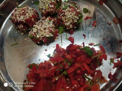 Oat-topped beetroot and tomato chaat with fresh coriander on stainless steel tray.