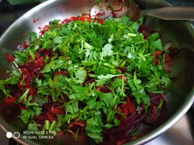 Fresh chopped cilantro on a colorful vegetable stir-fry in a stainless steel pan.