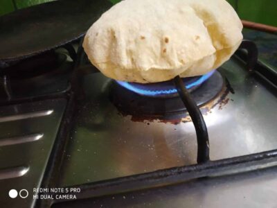 Soft Indian bread cooking on a gas stove flame, ready to be served.