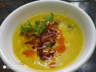 Creamy yellow lentil soup garnished with herbs and spicy toppings, delicious and comforting food.