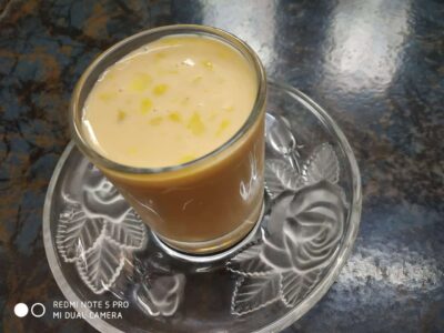 Sweetened milk with saffron and cardamom served in a glass on a decorative plate.