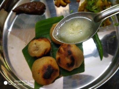 Golden fried snacks with spicy green chutney in a stainless steel platter.