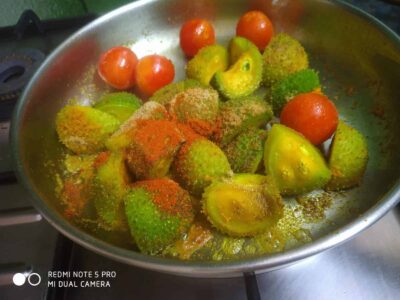 Fresh cut vegetables with spices ready for cooking, including tomatoes and green peppers.