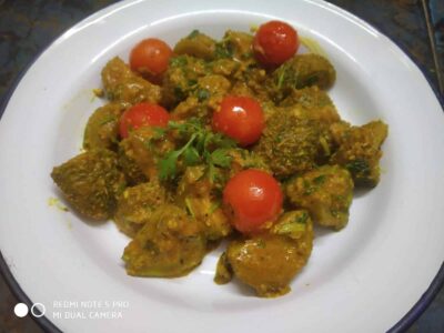 Spicy Indian Paneer Masala with cherry tomatoes and fresh coriander on a white plate.
