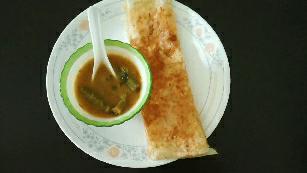 Crispy fried spring roll with dipping sauce on a white plate.