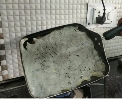 Burnt pancake stuck to frying pan, partially cooked breakfast disaster, kitchen cooking mishap.