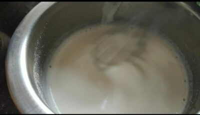 Creamy milk being boiled in a stainless steel pot.