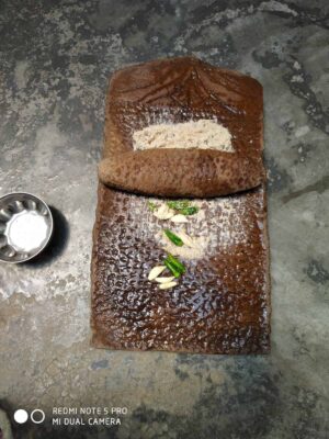 Rich chocolate brownie with chopped garlic and green chili garnishes.