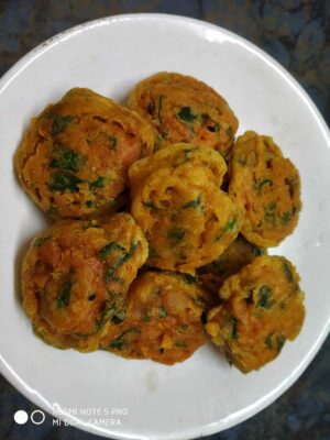 Deep-fried spicy vegetable fritters with herbs on a white plate, perfect for snacks or tea time.