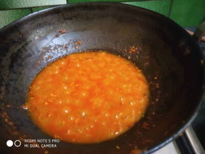 Bright orange tomato-based curry simmering in a black wok, ready to serve.