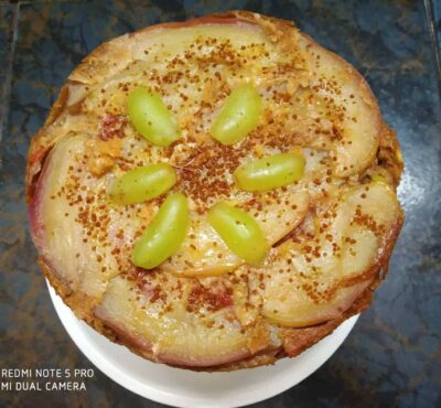 Golden potato and cheese cake topped with grapes and crispy spices, perfect for snack or dessert.