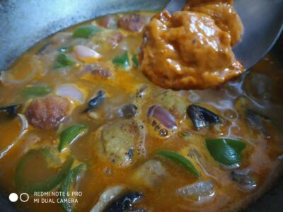 Spicy fish curry being cooked with vegetables in a wok, ready to serve delicious seafood dish.
