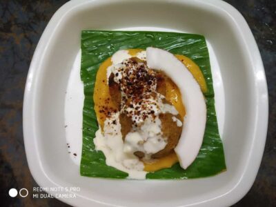 - Delicious Indian dessert with coconut, custard, ice cream, and chocolate sprinkles on banana leaf.