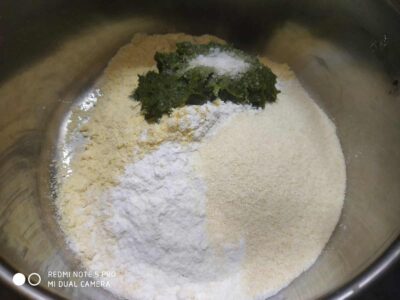 Flour, spinach, and spices in a mixing bowl for cooking or baking.