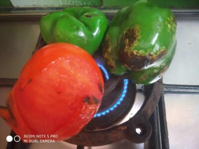 Colorful green and red bell peppers with signs of spoilage on a stove.