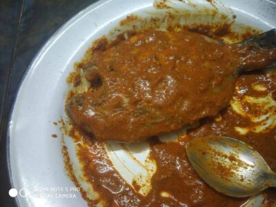 Spicy Fish Curry with Rich Tomato Gravy on White Plate, Traditional Indian Seafood Dish.